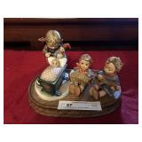 3 Hummel Figurines On Wooden Pedestal