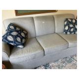 Upholstered couch, gray color with two pillows,