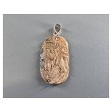Mammoth ivory pendant carved with variety of Alask