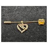 Gold colored stick pin  (Downstairs left)