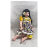 Vtg porcelain doll with black hair and a yellow,