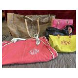 Bundle of purses, bags and faded red garment bag.