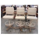 3 Cream-colored vintage swivel bar stools with a