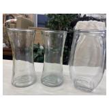 Set of three clear glass floral vases.