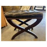 An X-frame curule stool featuring a tufted black