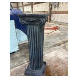 Dark, fluted classical column pedestal with an