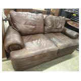 Distressed brown leather loveseat features