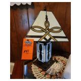 Tiffany-style stained glass table lamp featuring a pyramid-shaped shade with a Celtic or Trinity knot design and a geometric base