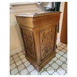 Vintage wooden storage cabinet featuring a distinct carved front panel.