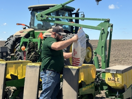 Adam Smith helps to load seed corn into a planter.