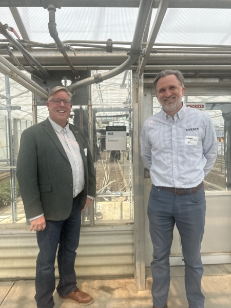 Sakata’s Justin Davis, Senior Sales & Marketing Director of Vegetables, and Kristopher Carlsson, Senior Research and Development Manager of Ornamentals pose next to Sakata Seed America’s greenhouse dedication plaque.