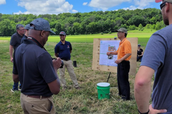 Wei Zheng (orange shirt) and Rabin Bhattarai (left of poster) speak about biochar at a field day.