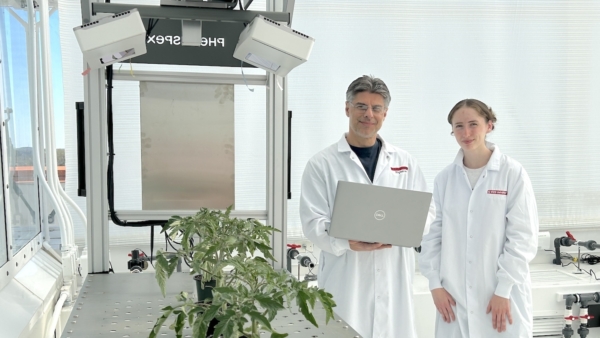 Joe Chiera, left, research project coordinator at the N.C. PSI greenhouse, and an NC State student worker check out the Phenospex plant phenotyping robot.
