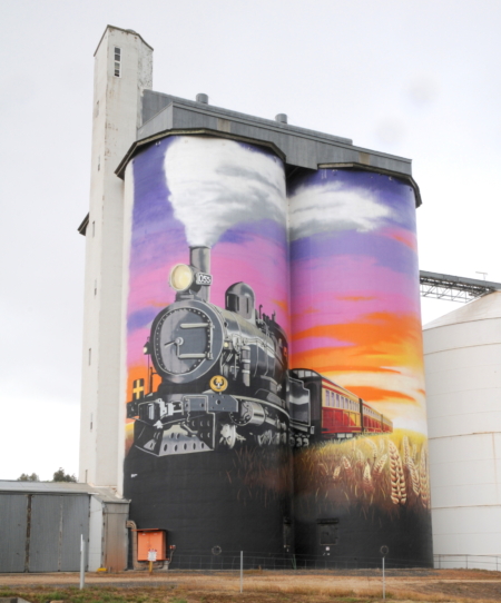 Completed 2020, 9th painted in Victoria, 45th to join Australia’s Silo Art Trail.
Jarrod Soden and Matthews Knights of Perpswet Designs completed the mural on Viterra’s silos in November 2020. More than 150 liters of paint and 140 hours of work depict Farrell Flat’s rich railroad history and the passing of the town’s final train.
Images courtesy of Bruce Selyem