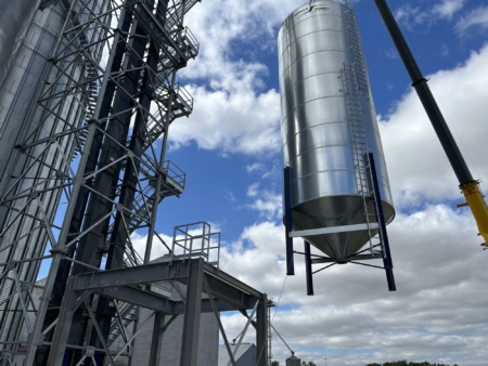 A crane lifts an overhead loadout tank into place during reconstruction.