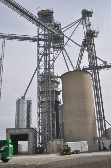 New construction from left includes a receiving pit with Schuld Bushnell screenings tank, Grain Flo tower enclosing a GSI receiving leg and Schlagel distributor, and two new overhead GSI belt conveyors.