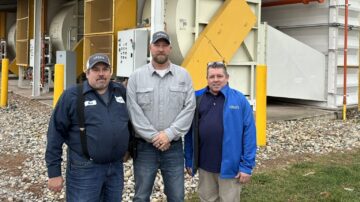 From left to right, Mark Larimer, Brad Trump, and David Larimer stand in front of one of the Lord’s Seed corn dryers. (Chris Lusvardi photo)