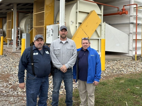 From left to right, Mark Larimer, Brad Trump, and David Larimer stand in front of one of the Lord’s Seed corn dryers. (Chris Lusvardi photo)