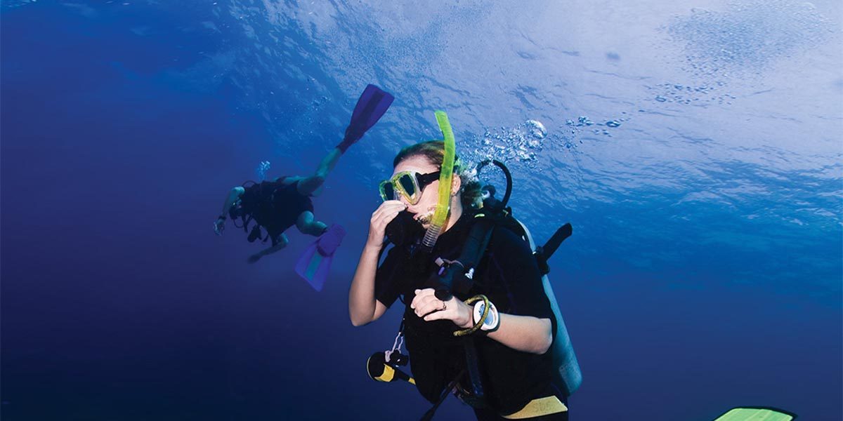 Scuba diver pinching nose to equalize ear pressure during descent underwater