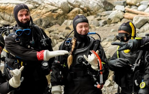 Two scuba divers adjusting equipment and preparing drysuits at Whytecliff Park Vancouver