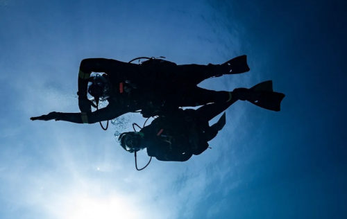 Diver holding wrist-mounted compass aligned along forearm for accurate underwater navigation