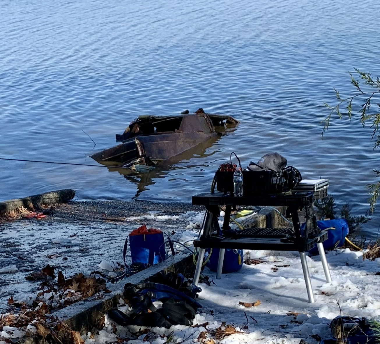 Public safety diver entering cold water from a snowy shoreline during a vehicle recovery operation in the Carolinas.