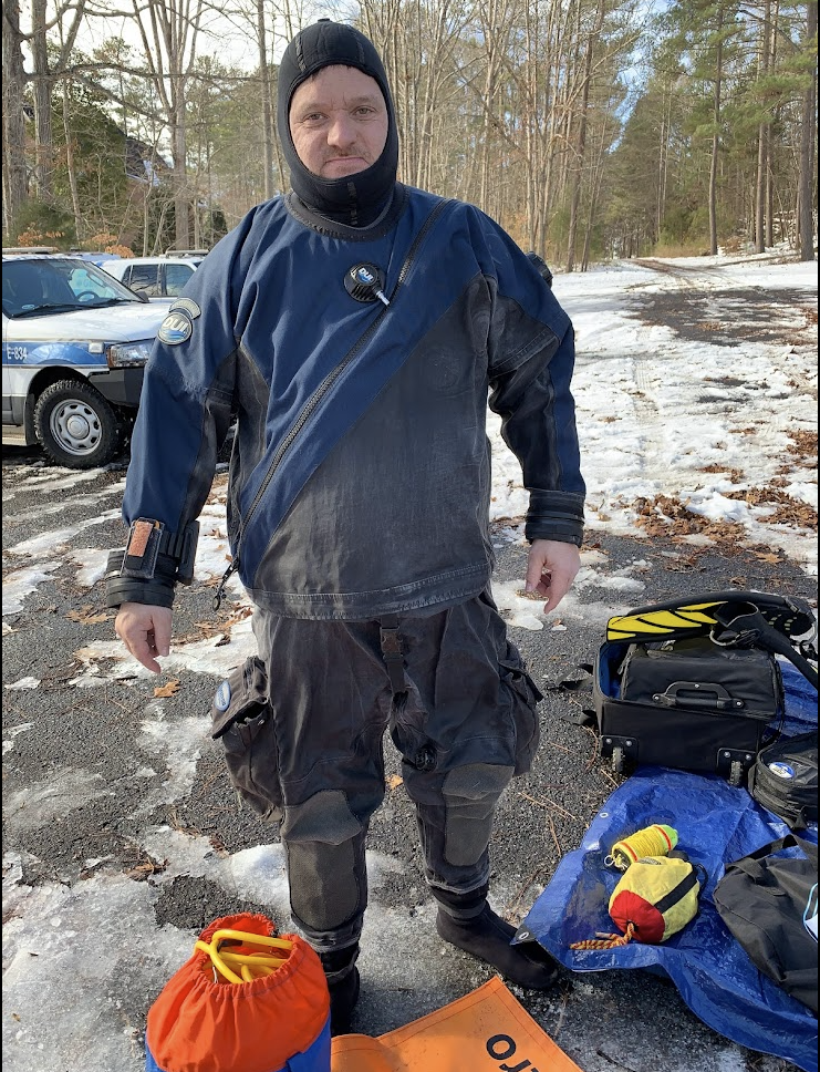 Public safety diver preparing to enter cold water from the shoreline during a vehicle recovery operation.