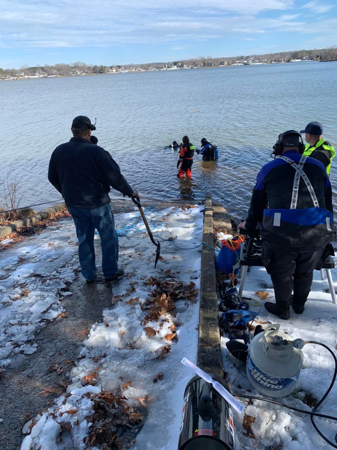 Public safety diver preparing to enter cold water from the shoreline during a vehicle recovery operation.