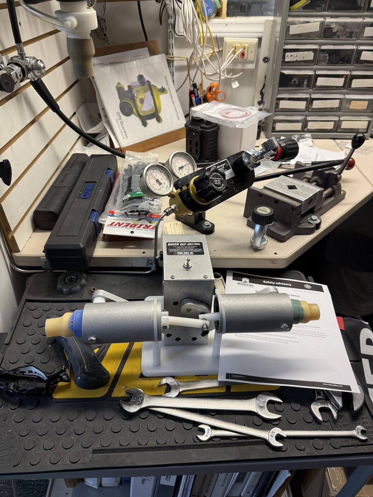 Regulator service bench at Sink or Swim Scuba with intermediate-pressure gauges, regulator vise, torque wrench and OTS Guardian service manual