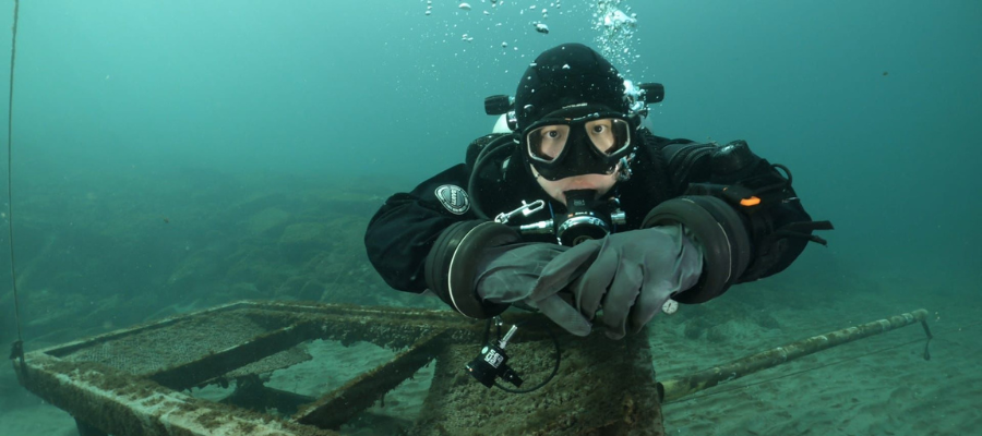 A scuba diver in a drysuit exploring a shipwreck