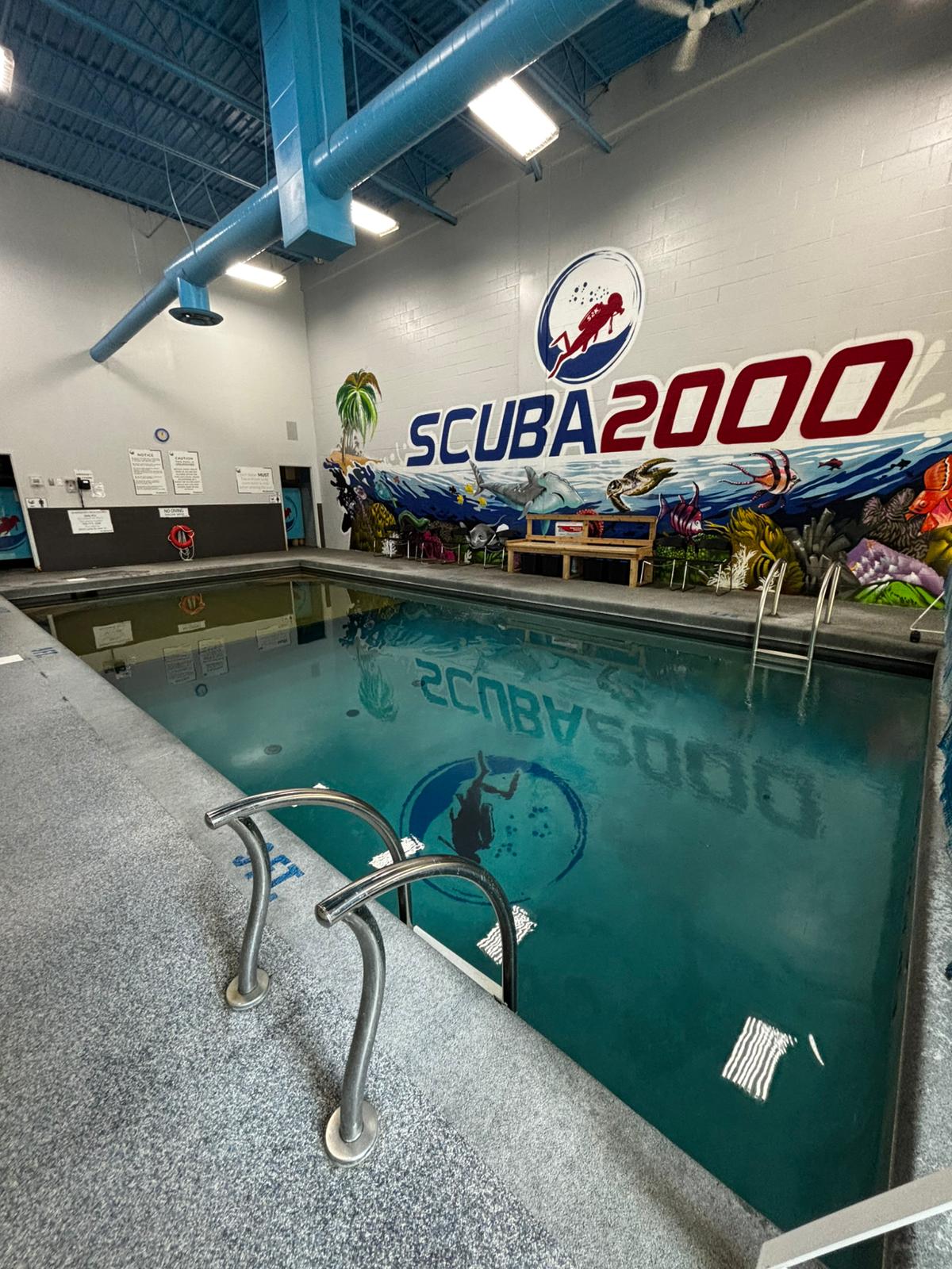 Scuba 2000 indoor pool with the shop logo and underwater mural on the wall
