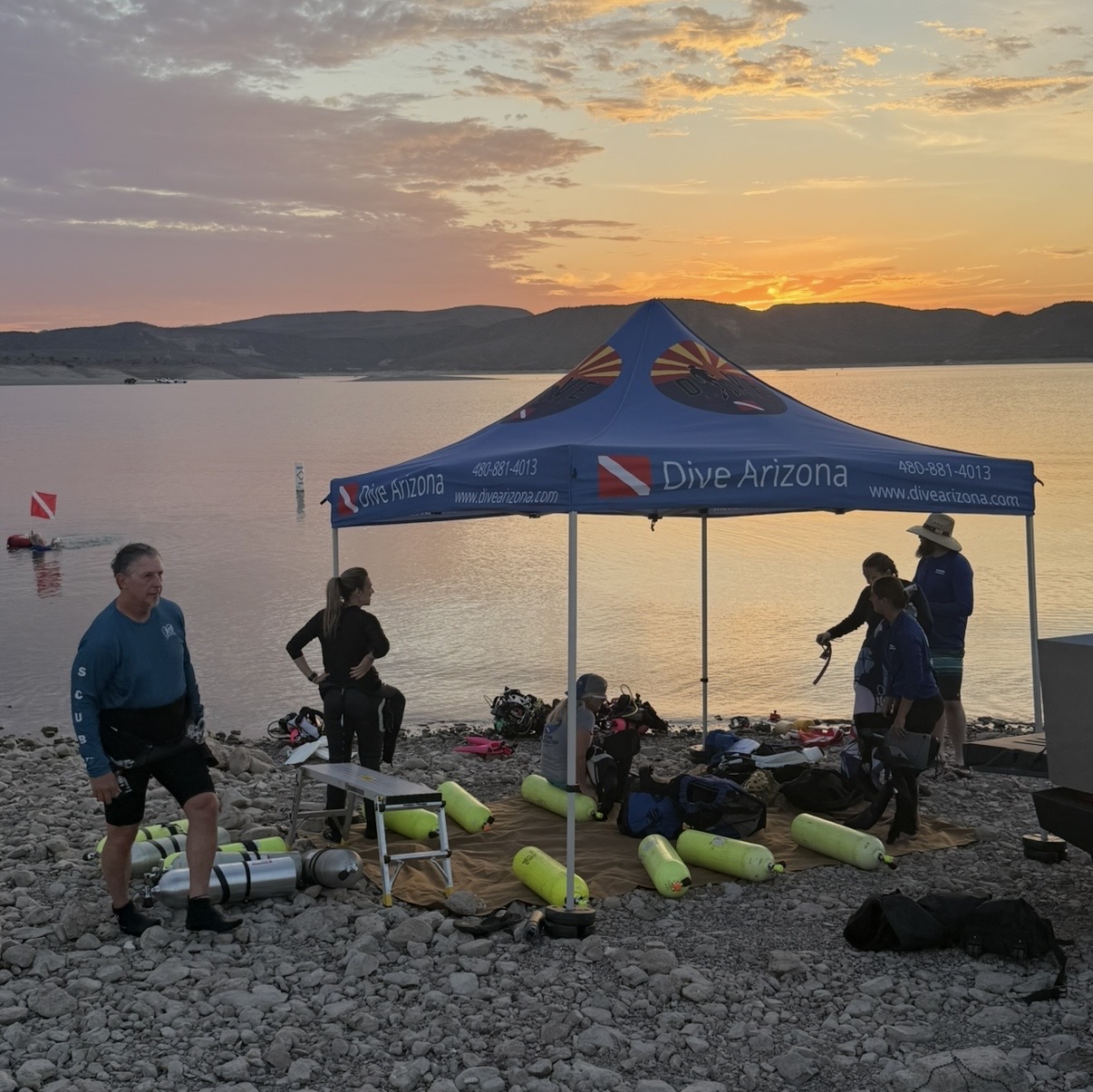 Dive Arizona group and staged gear under the shop tent at sunset before a Lake Pleasant dive