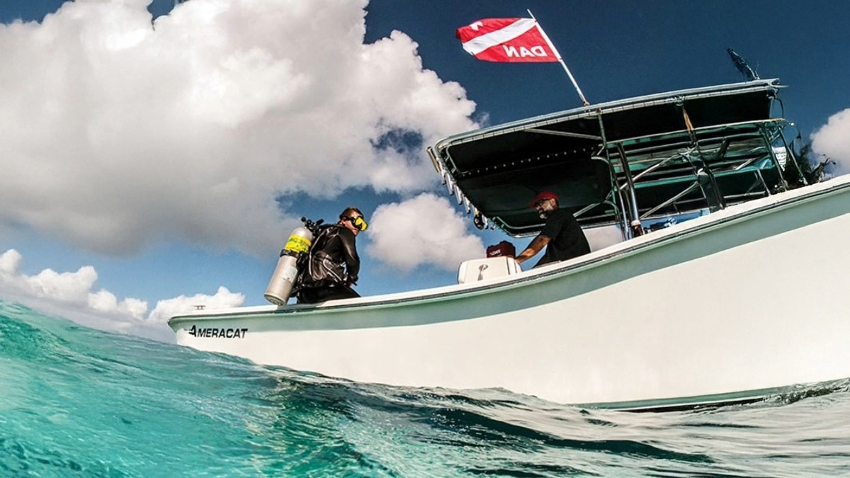 Diver preparing to enter the water from a boat flying a DAN safety flag