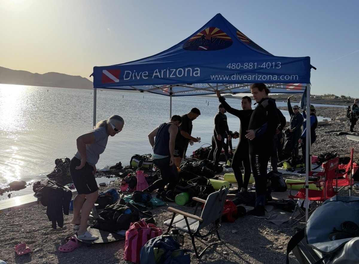 Divers gearing up under the Dive Arizona shop tent on the shore of an Arizona lake at sunrise
