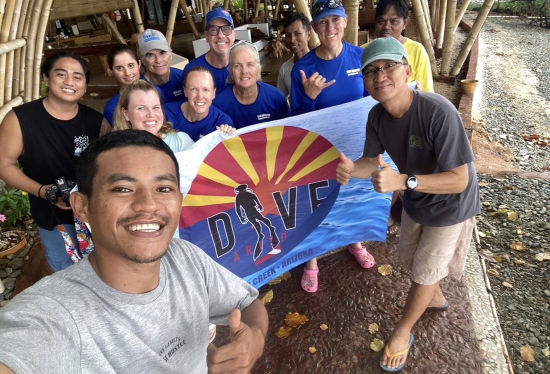A group of Dive Arizona divers holding a Dive Arizona flag together on a group dive trip