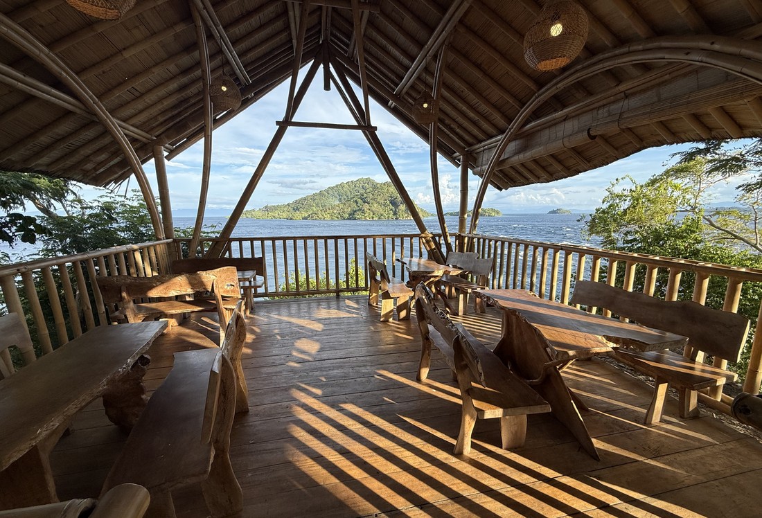 An open-air bamboo resort pavilion overlooking the ocean at a dive trip destination