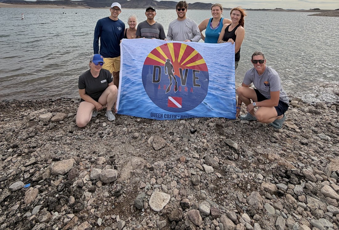 Dive Arizona staff and divers holding the Dive Arizona flag together on a lake trip