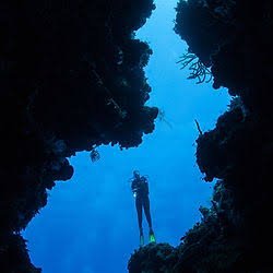 A diver silhouetted in a volcanic canyon in St. Vincent