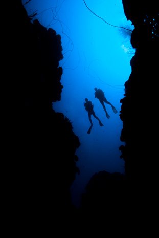 Two divers silhouetted in the Grand Canyon dive site at St. Eustatius