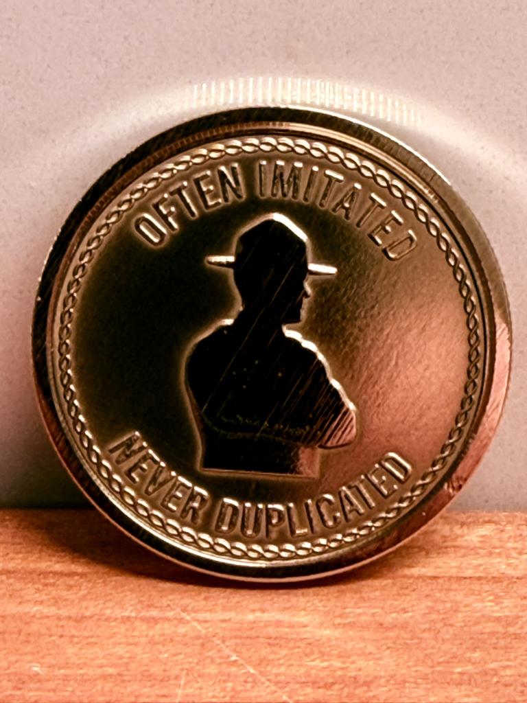 Close-up of custom engraved challenge coin, 'Often Imitated' detail