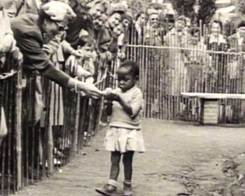 At a “Peoples Shows” in Brussels, Belgium, where a young Black girl is fed by spectators. Image: Public Domain