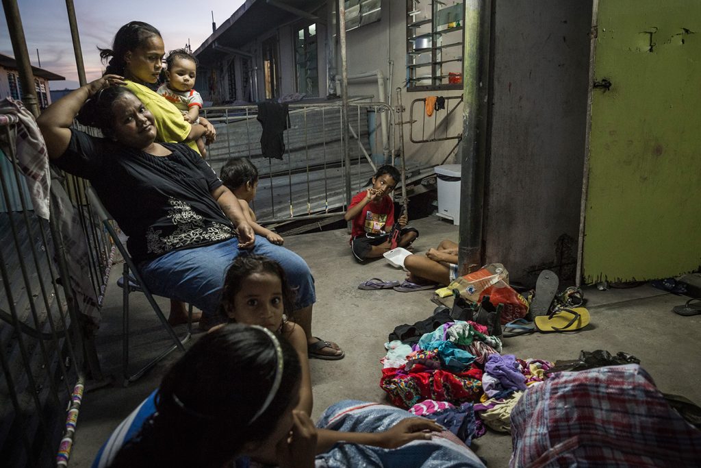 A Nauruan family sits outside their house in the Location Block Area. Location Block was a residential area for foreign miners who came to Nauru to work on the phosphite mine. After the closure of the mine in the early 2000s most of the miners left Nauru and the Location Block became a squatters settlement, mostly populated by locals. Image by Vlad Sokhin
