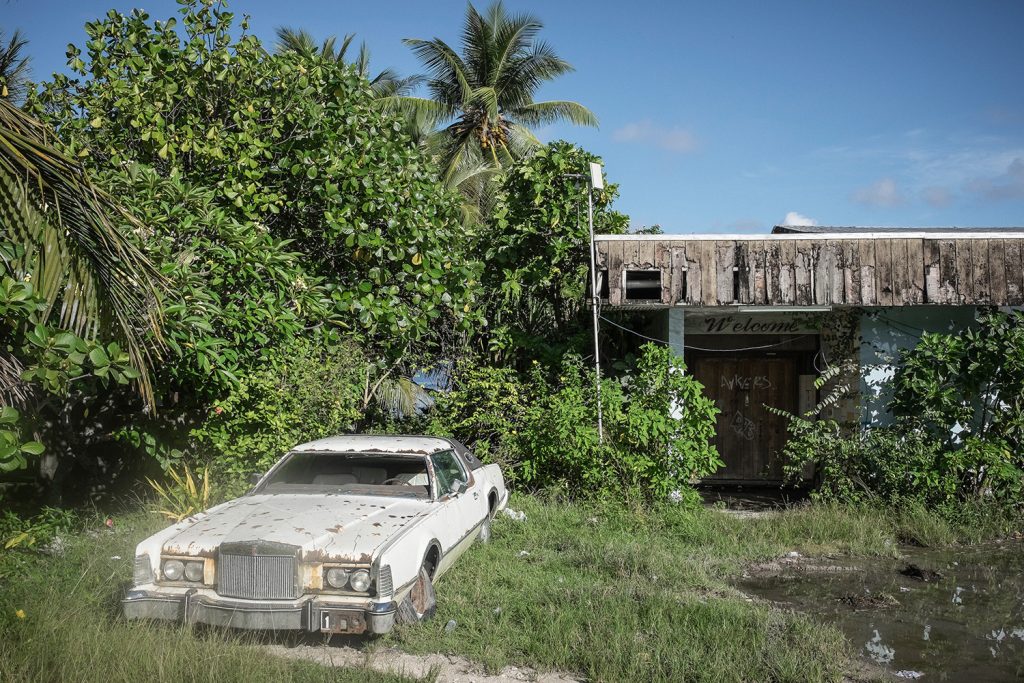 An abandoned vehicle stands by the side of a road. Many cars have been abandoned along Nauru's roads and in backyards. With an unemployment rate of around 90%, much of the population is dependent on government handouts which are becoming increasingly unaffordable with the sharp reduction in phosphate output on the island. Image by Vlad Sokhin