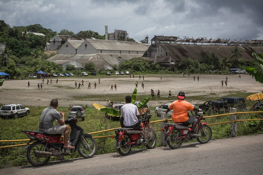 People watch an Australian rules football game in front of the Phosphate processing factory. The sport is very popular in Nauru and, along with weightlifting, is the national sport of the island nation. Image by Vlad Sokhin