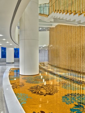Three-story Lobby featuring 80-foot curved, cast gold tile wall and shimmering mosaic tile waterbody