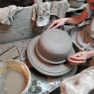 An artisan carefully crafting a large clay pot