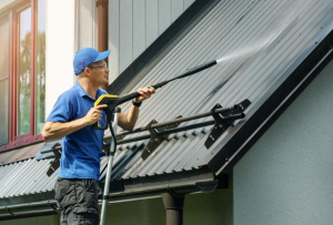 A pressure washing expert power washing a roof