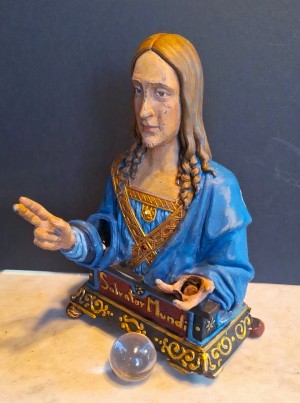 Jesus’s right arm makes blessing motion while the coin, in left hand, drops into the base of the b
