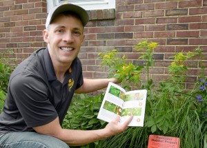 Author and editor, Scott Schmidt, holds the book next to Golden Alexanders in his pollinator garden.