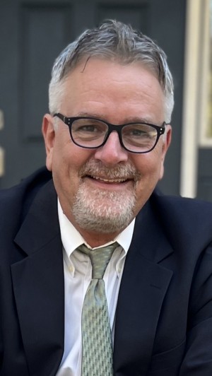 James Seidel in a dark suit with a patterned tie and a white shirt